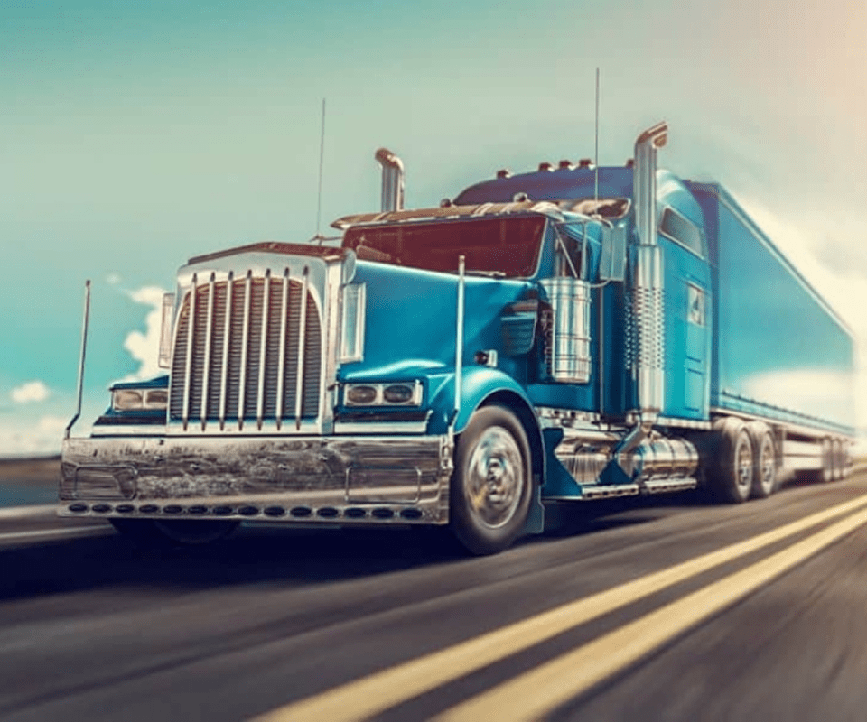 Blue semi-truck driving on a highway.
