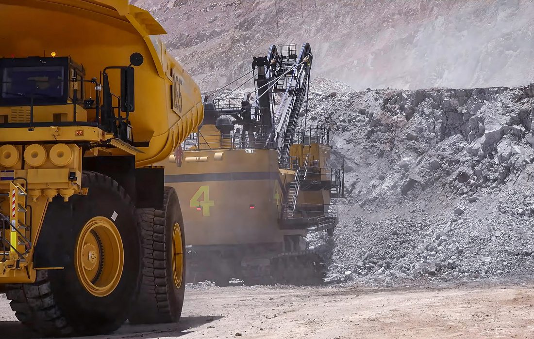 Mining trucks and excavator in rocky landscape.